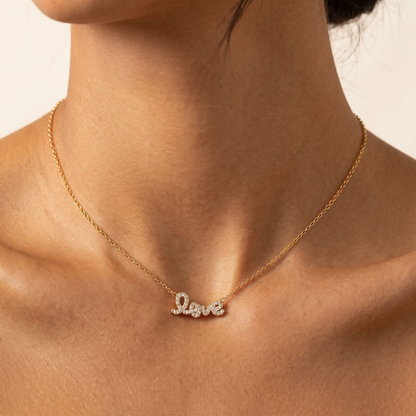 Woman wearing the Manon crystal love script gold necklace at the collarbone