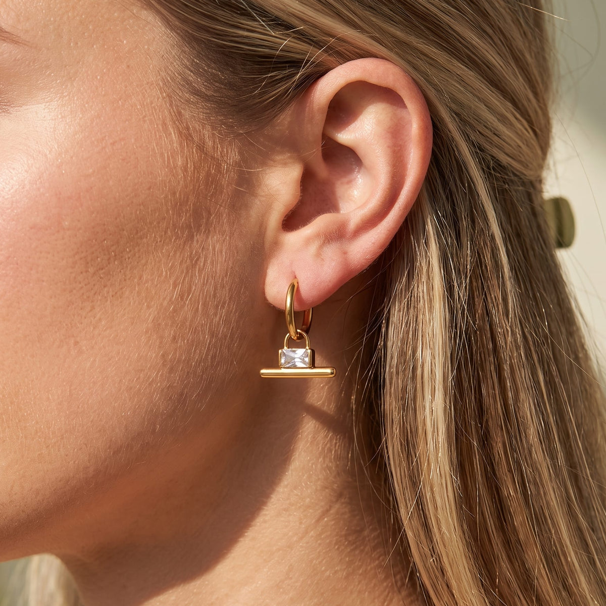 Woman wearing the Margaux padlock t-bar gold earrings on her ear close up