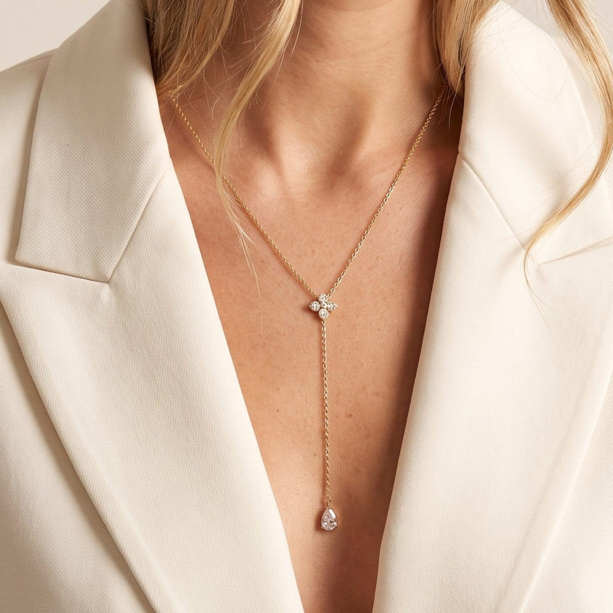 Woman wearing the Marguerite flower lariat gold necklace at the collarbone, with a white blazer