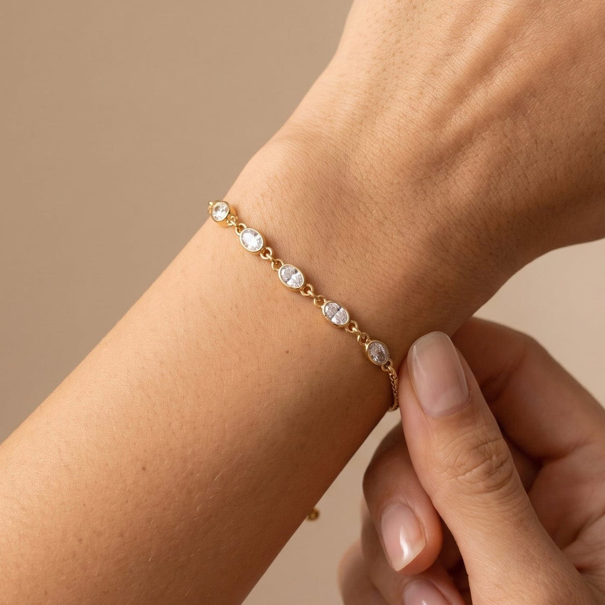 Woman wearing the Marisa oval crystal gold bracelet on the wrist, adjusting the chain