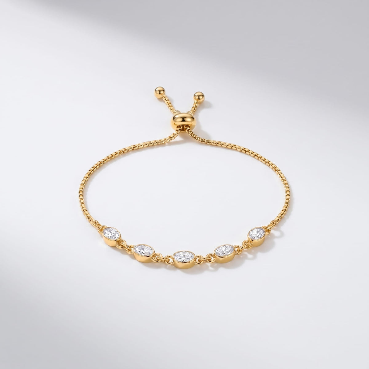Marisa oval crystal gold bracelet on a white surface with five bezel set stones