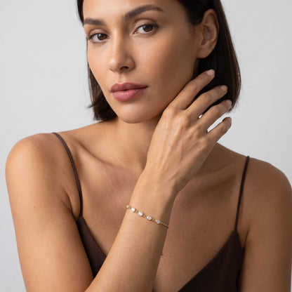 Woman wearing the Marisa oval crystal gold bracelet on the wrist in a brown top