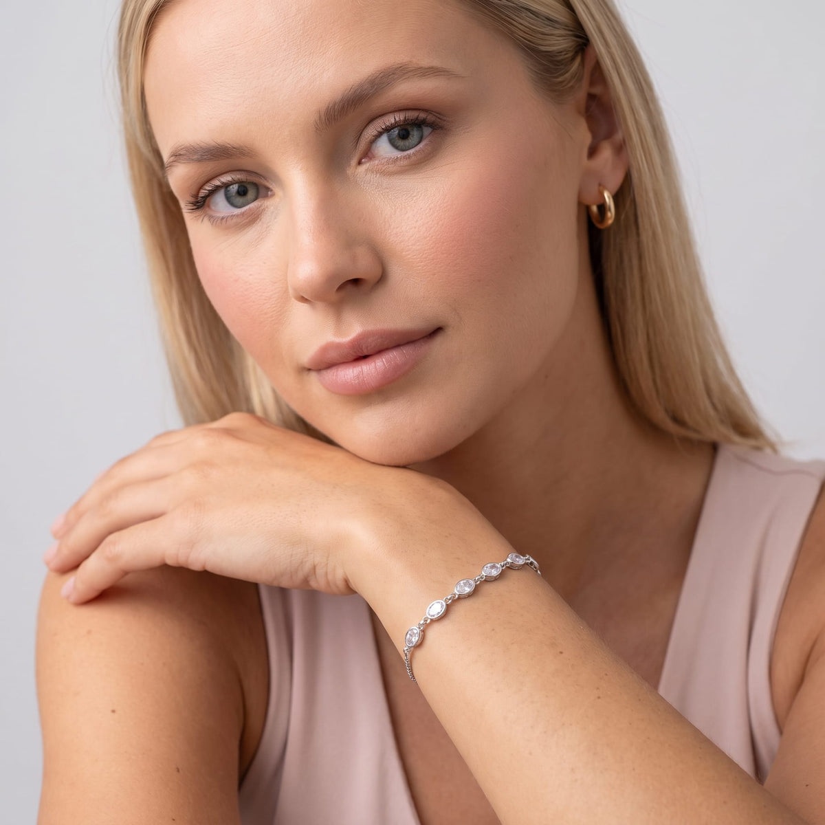 Woman wearing the Marisa oval crystal silver bracelet on the wrist resting her chin on her hand