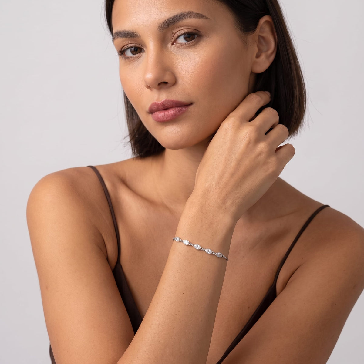 Woman wearing the Marisa oval crystal silver bracelet on the wrist resting her hand near neck