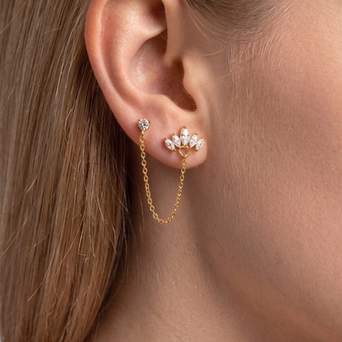 Double-piercing gold earring: crystal stud linked by a fine chain to a marquise crystal crown