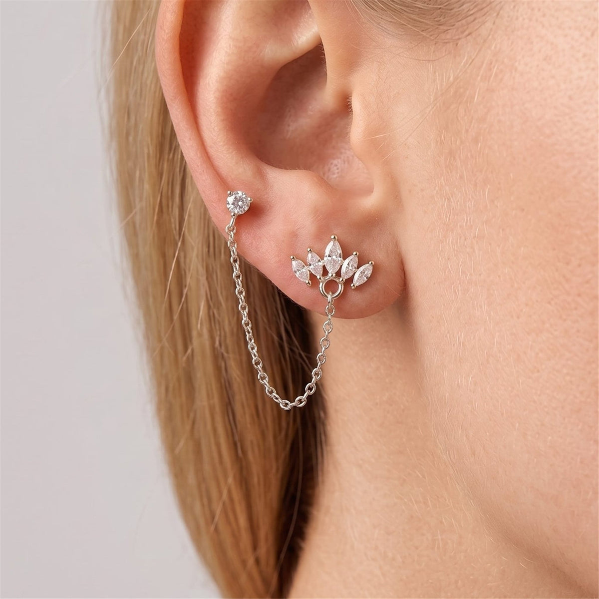 Silver double-piercing set on the ear, a crystal stud chained to a marquise crystal crown stud