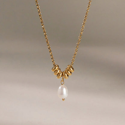 Mathilde pearl drop necklace hanging against a soft taupe backdrop