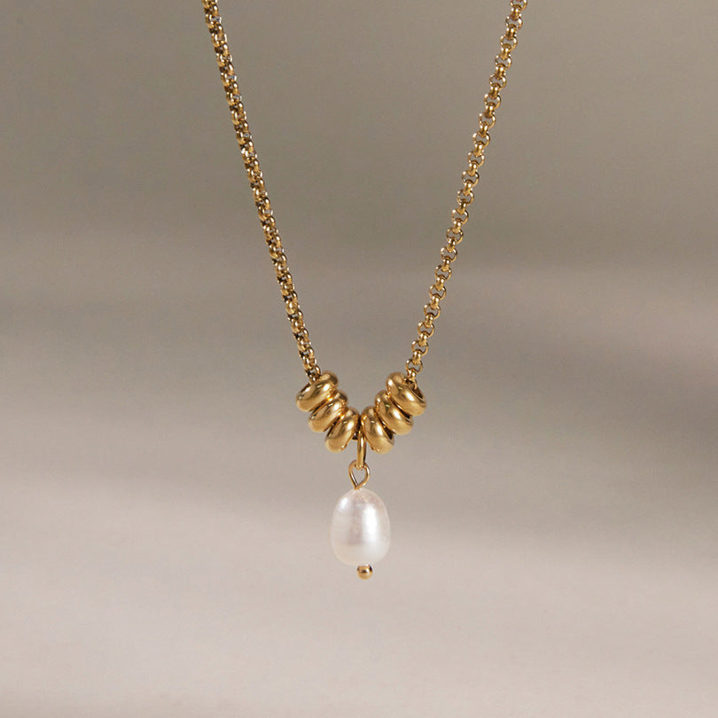 Mathilde pearl drop necklace hanging against a soft taupe backdrop