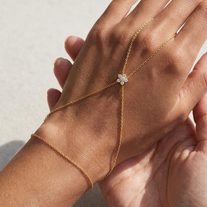 Woman wearing the Mélisa gold hand chain, fine chains meeting at a crystal flower on the back of the hand