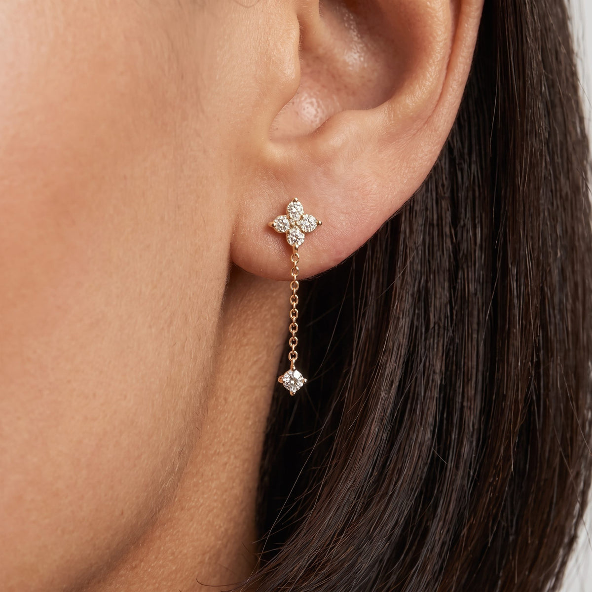 Woman wearing the Mia crystal drop earring in gold, a crystal flower stud with a chain drop