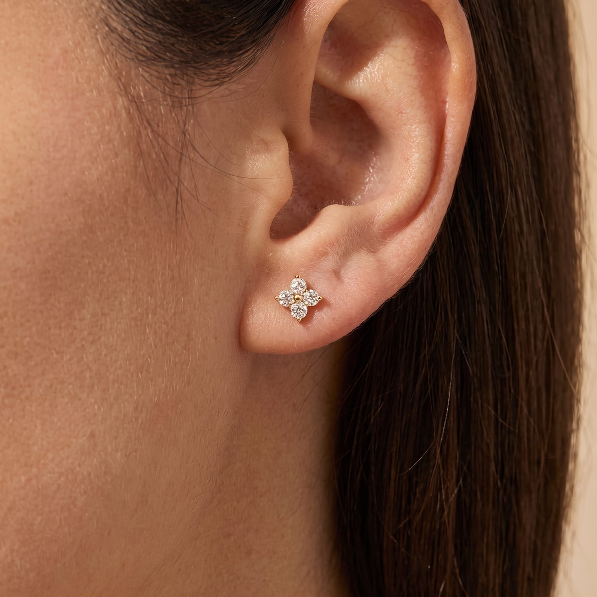 Woman wearing the Mia gold stud, a clover of four clear crystals sitting on the lobe