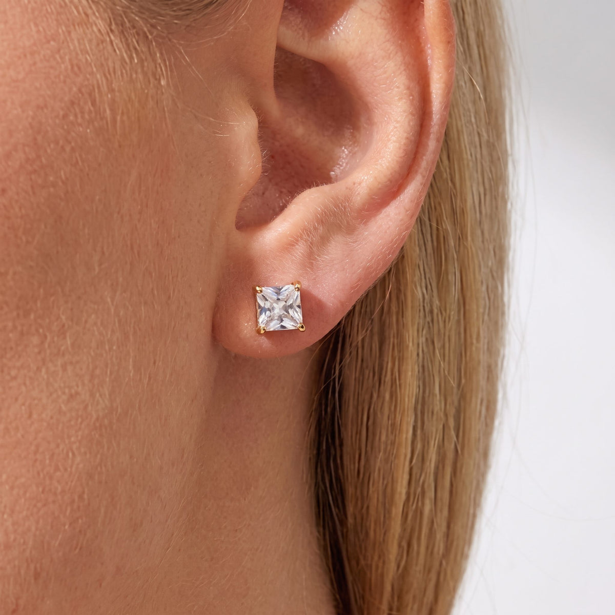 Woman wearing the Mia square crystal stud in a four-prong gold setting