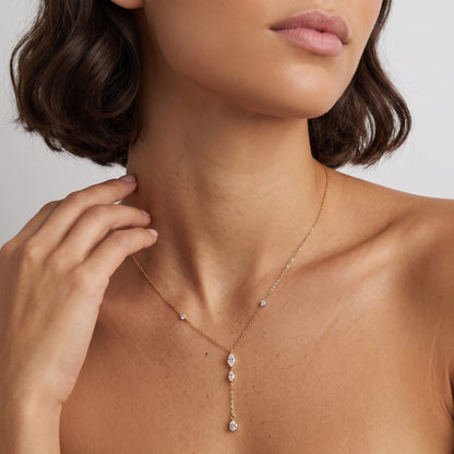 Woman wearing the Mireille marquise drop gold necklace at the collarbone, gently touching her neck