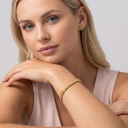 Woman wearing the Nicoletta puffed link gold bracelet on the wrist resting against her chin