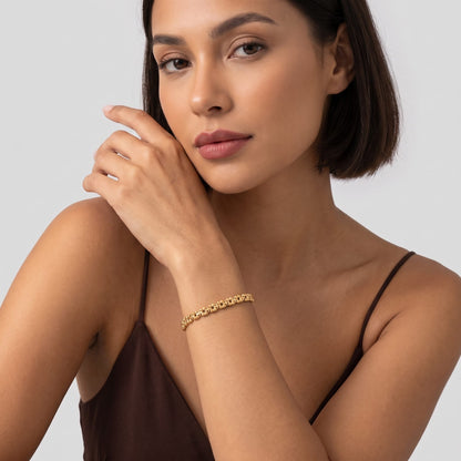 Woman wearing the Nicoletta puffed link gold bracelet on the wrist wearing a brown camisole top