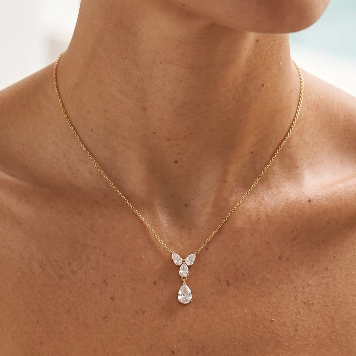 Woman wearing the Noémie crystal teardrop gold necklace at the collarbone