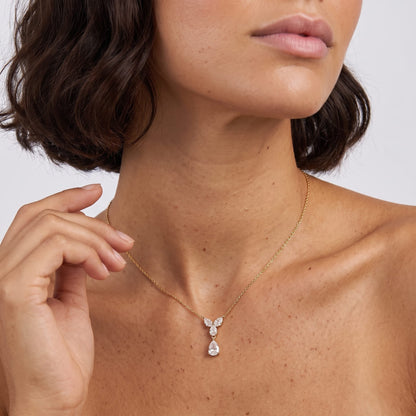 Woman wearing the Noémie crystal teardrop gold necklace at the collarbone with hand raised to her neck