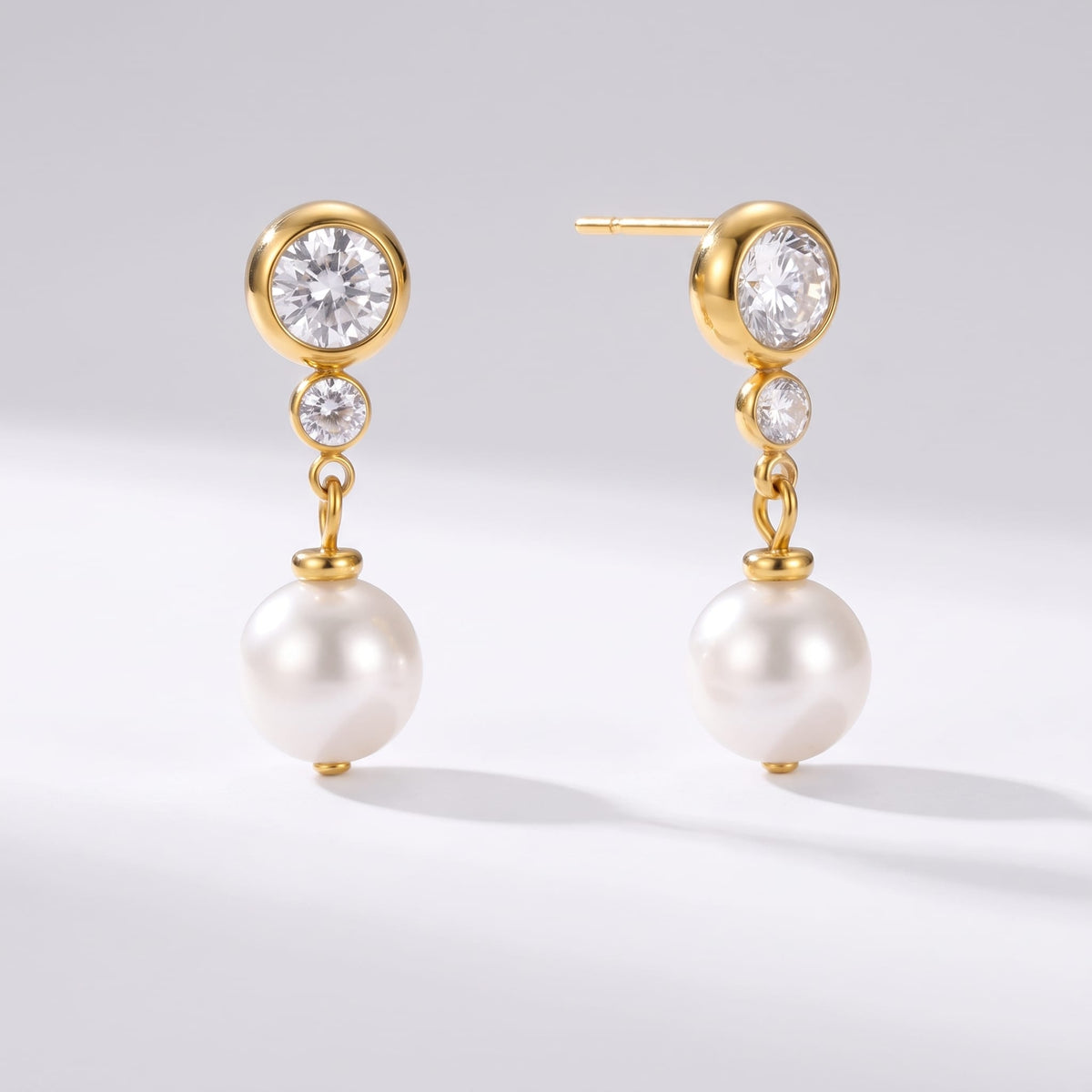 Odette crystal pearl gold earrings on a plain white surface casting soft shadows