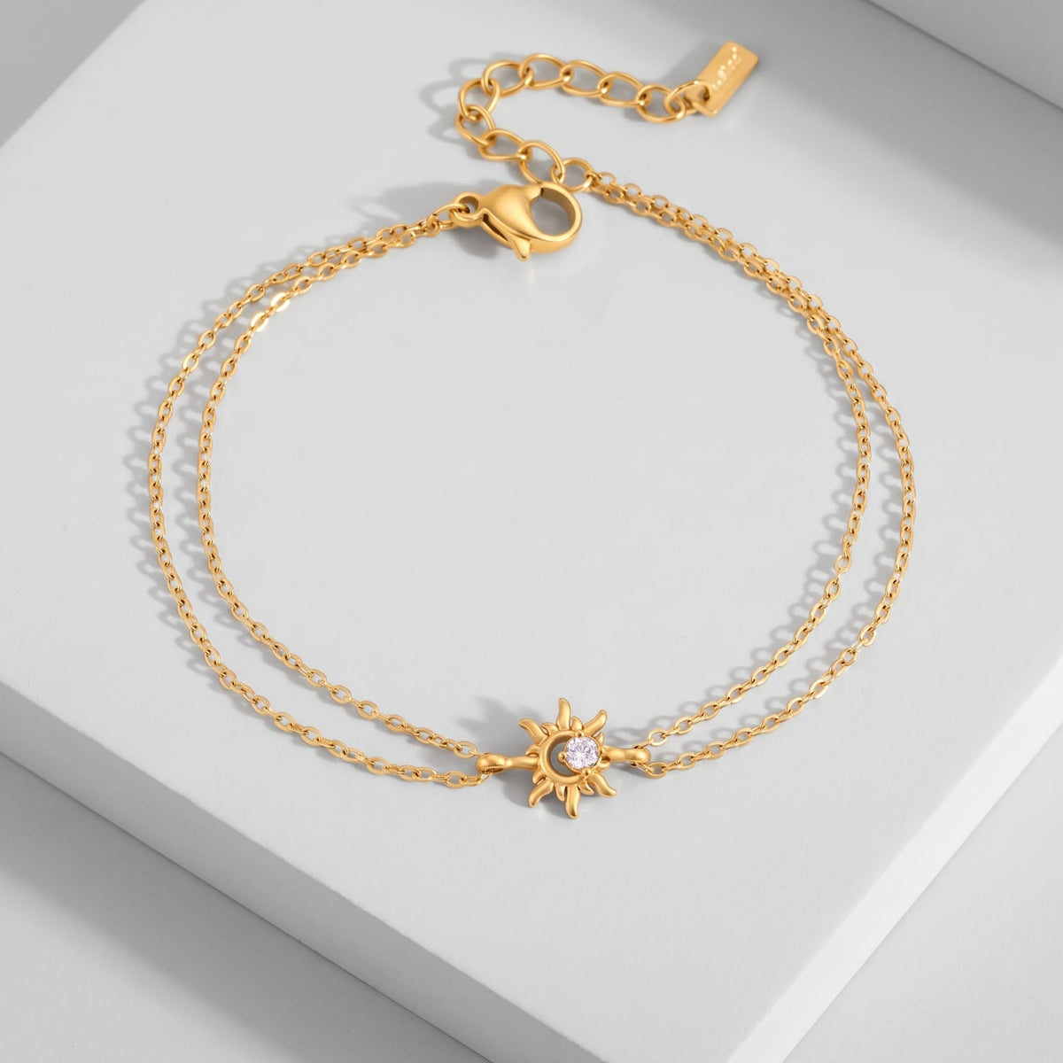 Olivia crystal sun gold bracelet on a white platform displaying the double chain and sun charm