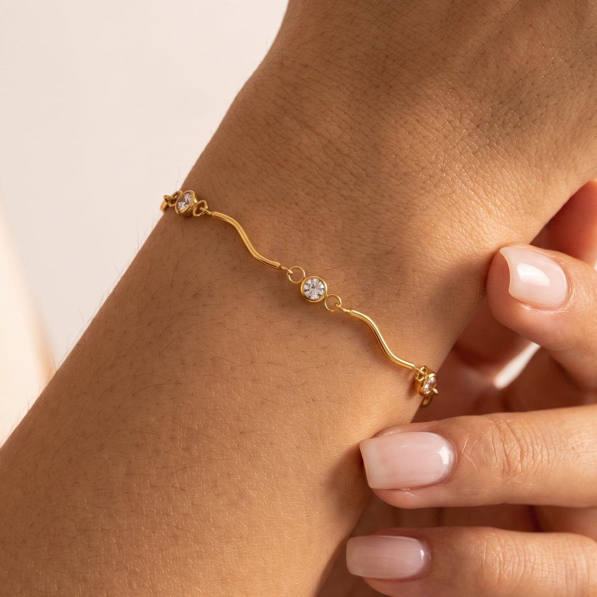 Woman wearing the Luna wave crystal gold bracelet on the wrist