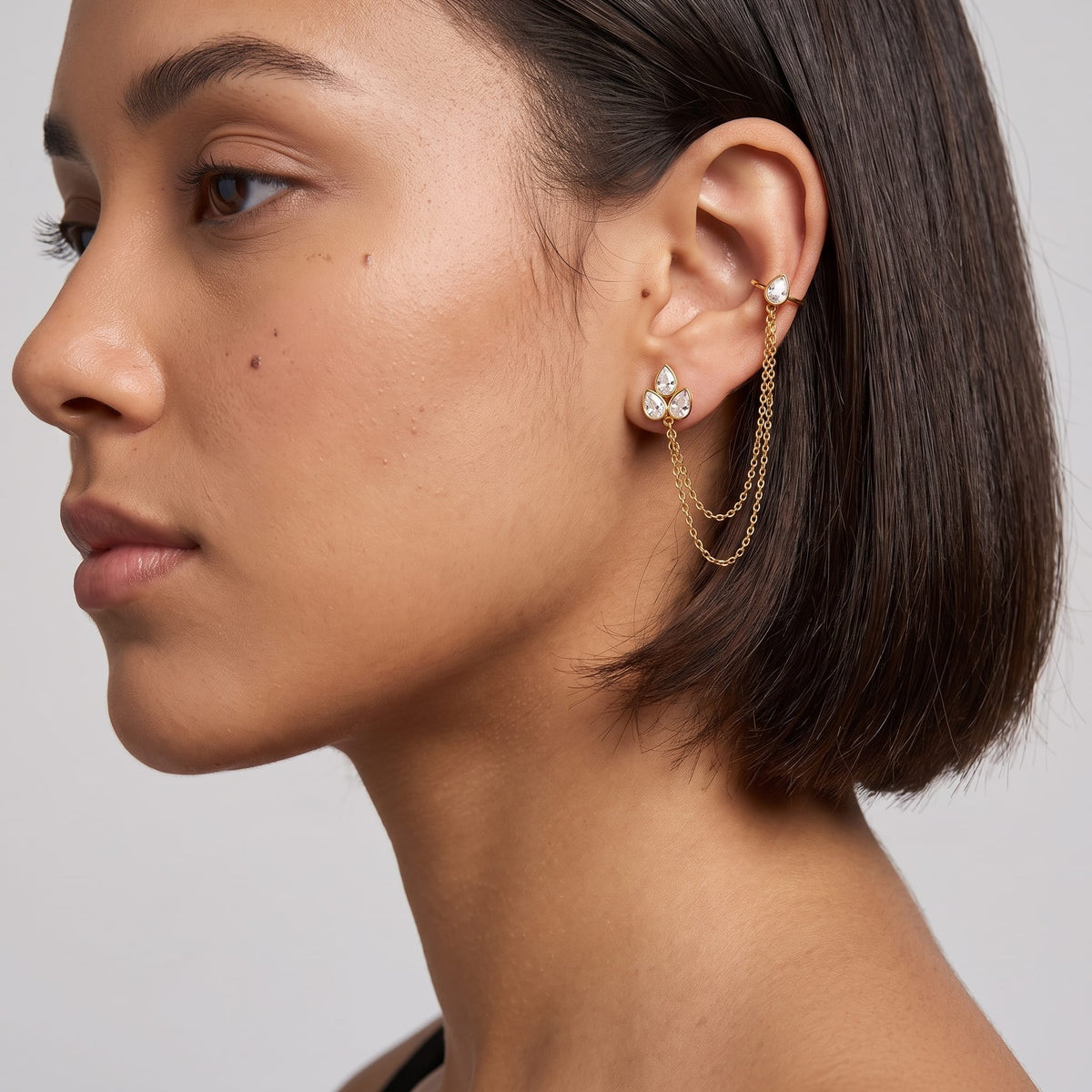 Woman wearing the Ophélie cuff chain gold earrings on her ear with short dark hair