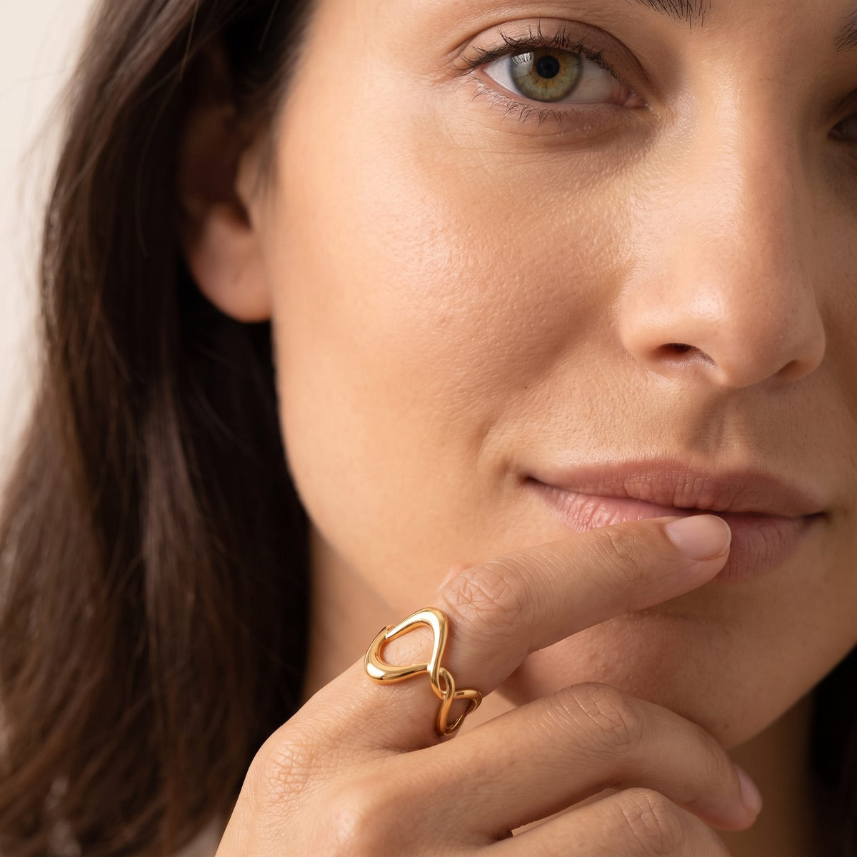 Woman wearing the Ophélie twisted wave gold ring on the hand touching her lower lip