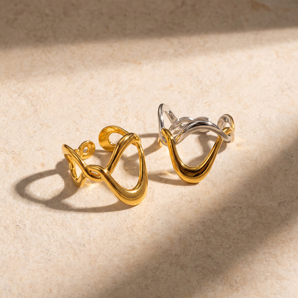 Ophélie silver and gold wave ring standing upright on warm beige stone in soft shadow