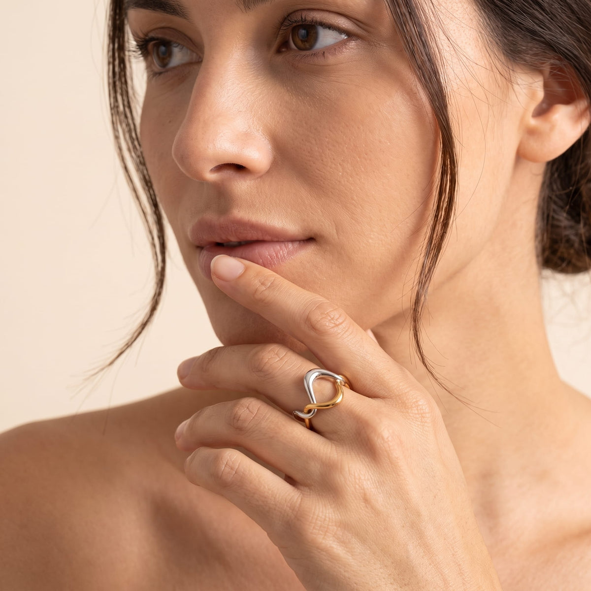 Woman wearing the Ophélie twisted wave two-tone ring on the hand posed against her chin