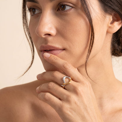 Woman wearing the Ophélie twisted wave two-tone ring on the hand posed against her chin