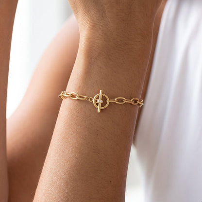 Woman wearing the Ornella circle toggle gold bracelet on the wrist, toggle clasp centered