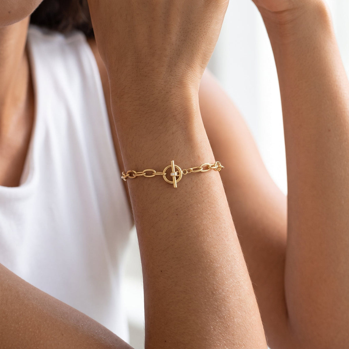 Wider view of a woman wearing the Ornella circle toggle gold bracelet on the wrist, toggle clasp centered