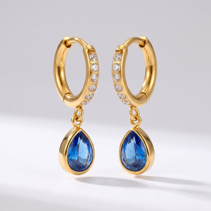 Paola blue teardrop gold earrings on a plain white background