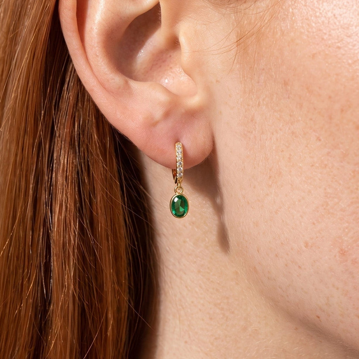 Woman wearing the Paola green oval gold earrings on the ear