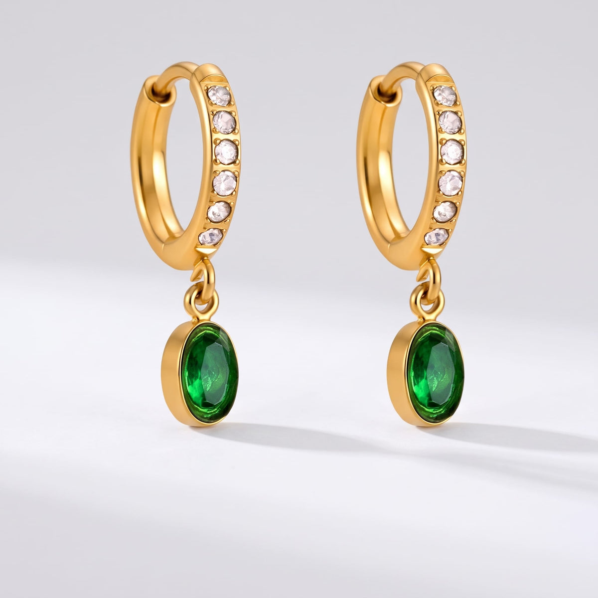 Paola green oval gold earrings on a plain white surface
