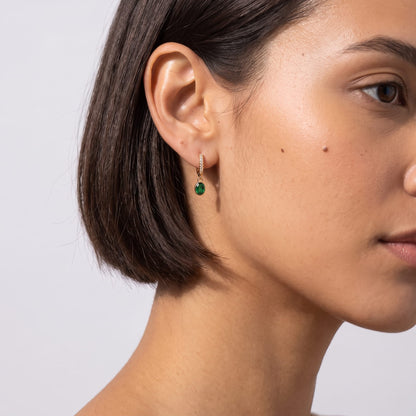 Woman wearing the Paola green oval gold earrings on the ear with short dark hair