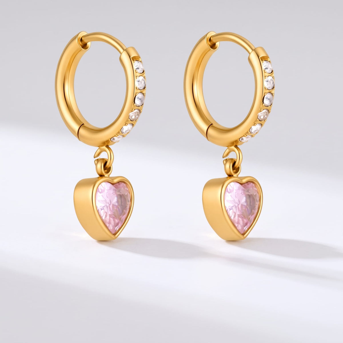 Paola pink heart gold earrings on a white surface with clear shadows