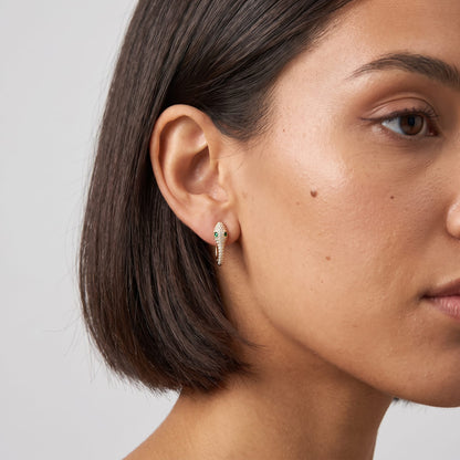 Woman wearing the Sabine pavé snake gold earrings on the ear with dark hair