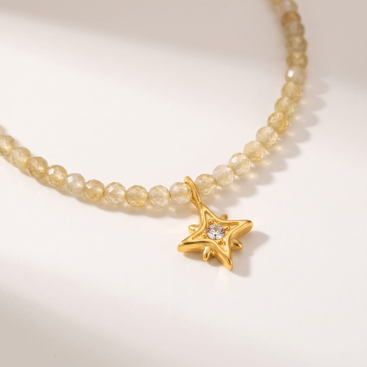 Selene star gemstone gold necklace on a white surface with close detail on the star pendant