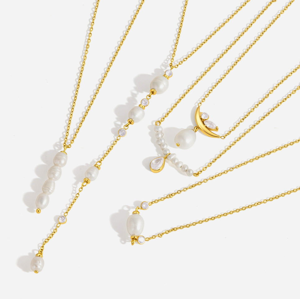 Serena oval pearl station necklace at the bottom of a group of gold pearl necklaces on white