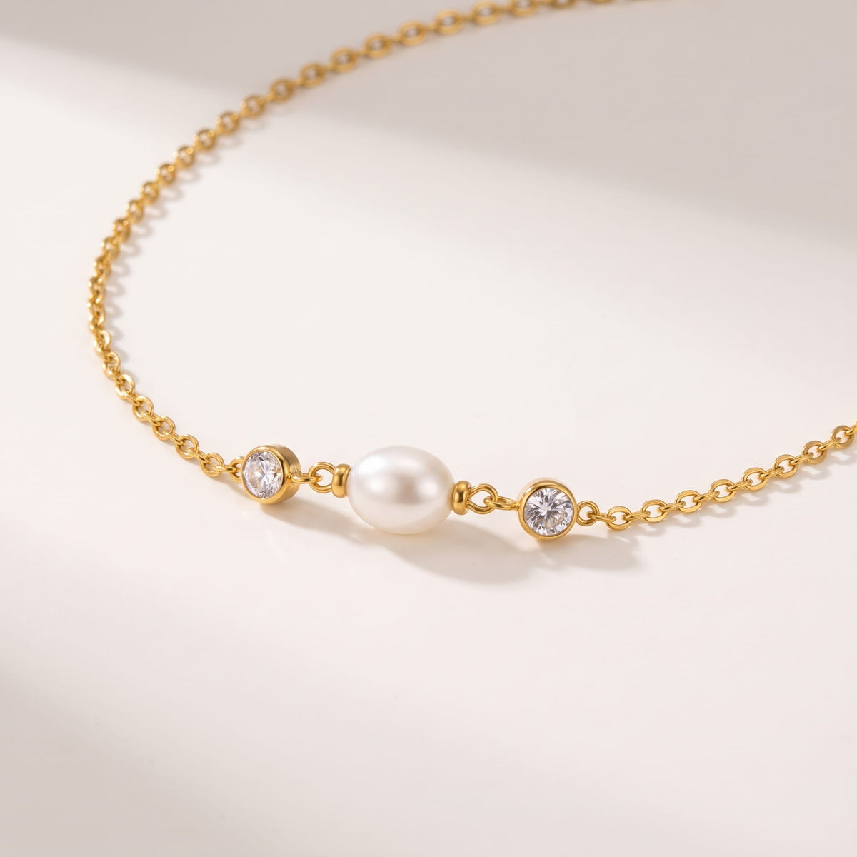 Serena single pearl gold necklace on a white surface in soft warm sunlight