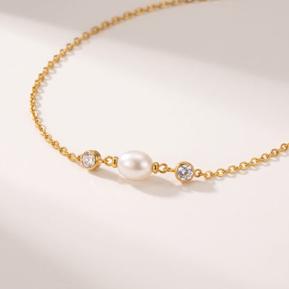 Serena single pearl gold necklace on a white surface in soft warm sunlight