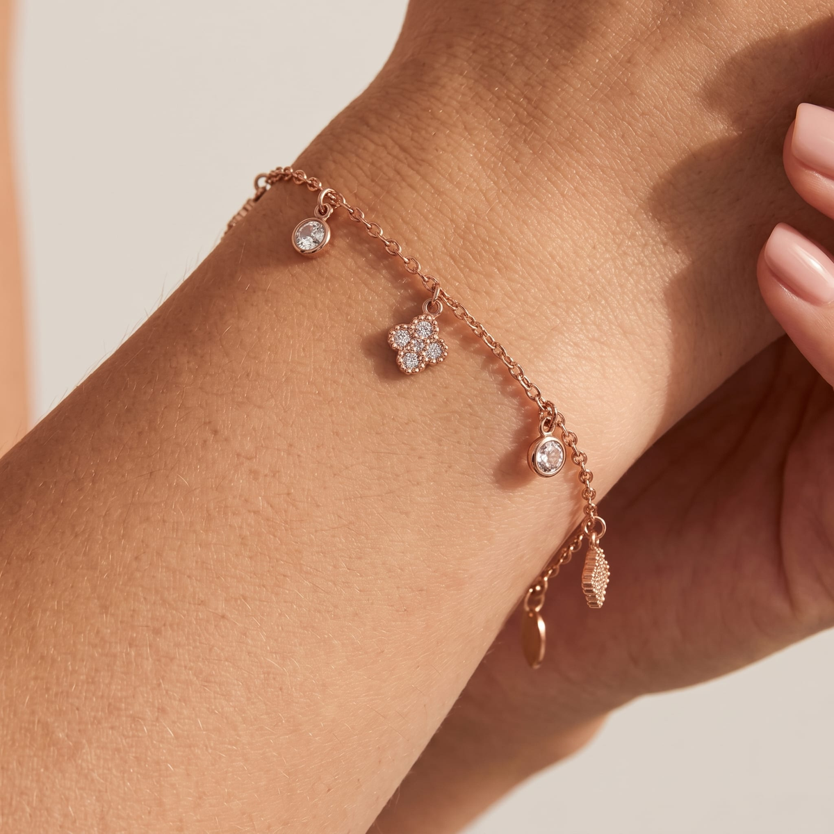 Woman wearing the Sienna gold bracelet with a crystal clover, round crystal drops and a leaf charm