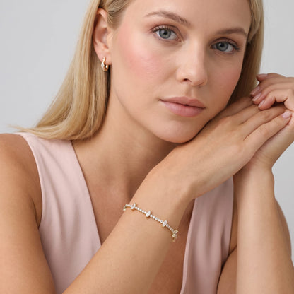 Woman wearing the Sienna marquise tennis gold bracelet on the wrist in a pink top