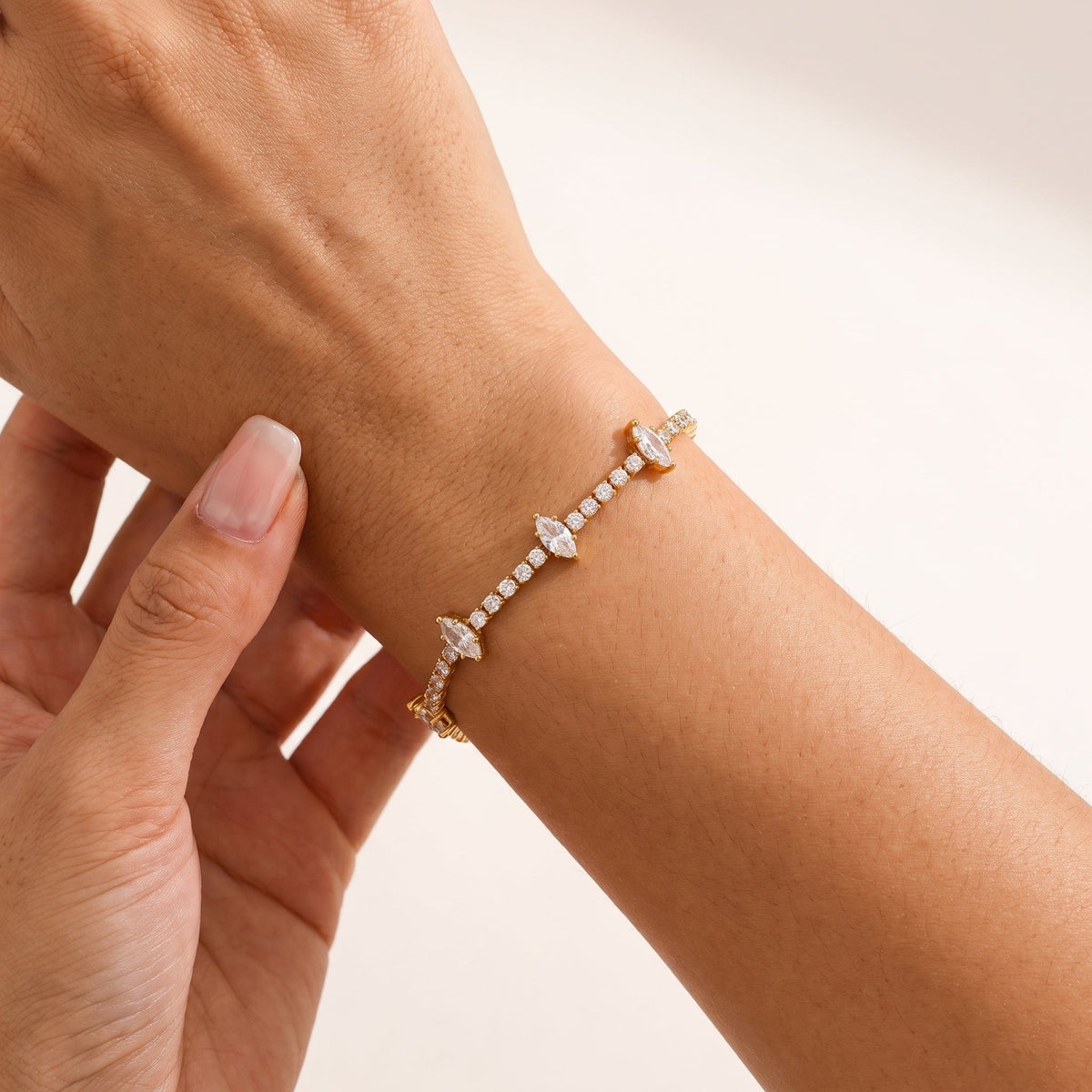 Wider view of a woman wearing the Sienna marquise tennis gold bracelet on the wrist