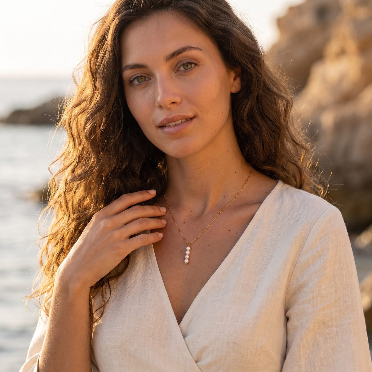 Woman wearing the Simone stacked pearl gold necklace at the collarbone outdoors in a white dress
