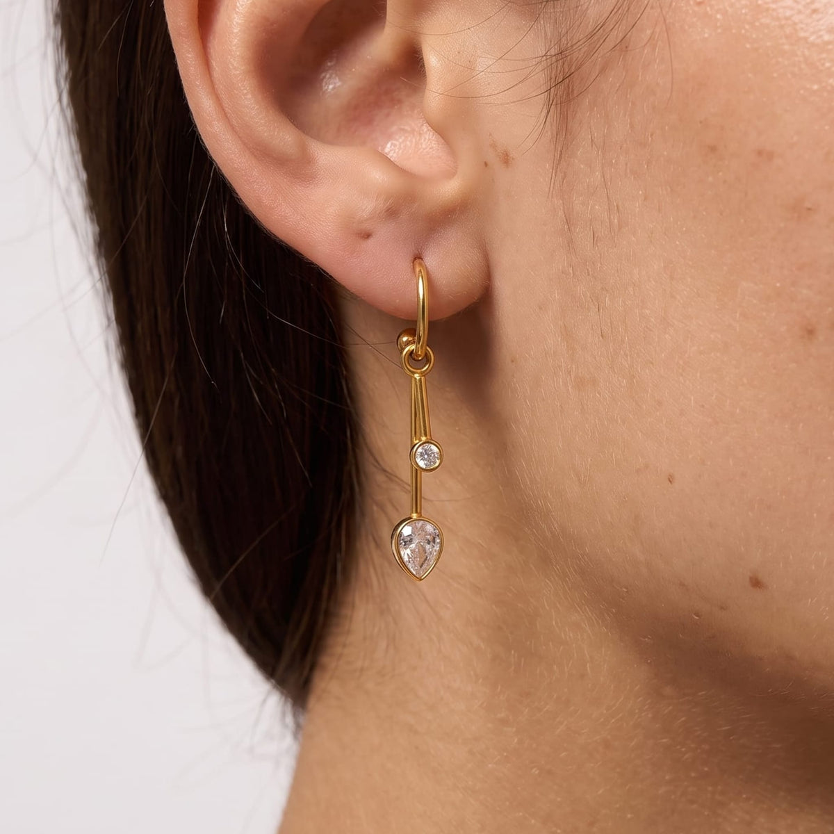 Woman wearing the Sixtine crystal bar gold earrings on her earlobe in a close profile photo