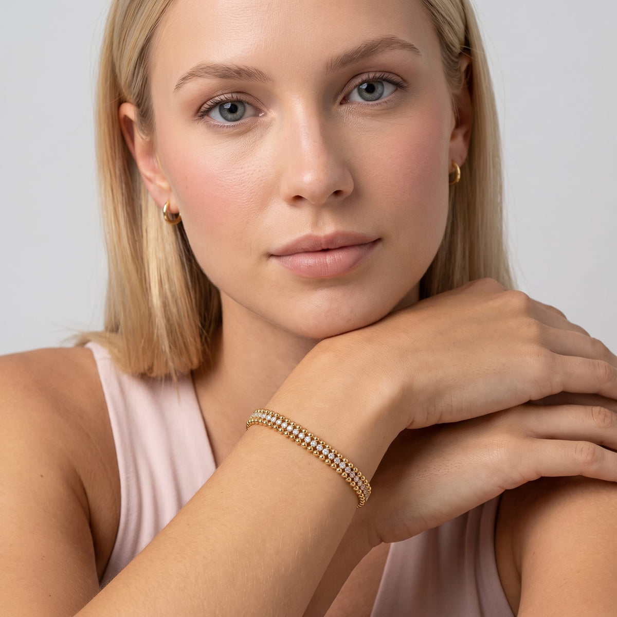 Woman wearing the Sofia bead tennis gold bracelet on the wrist while resting chin on hand