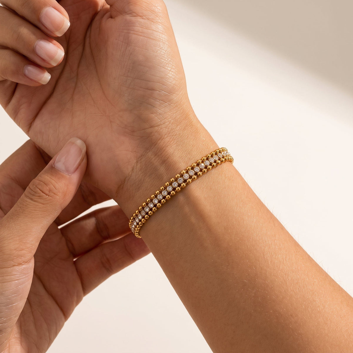 Wider view of a woman wearing the Sofia bead tennis gold bracelet on the wrist