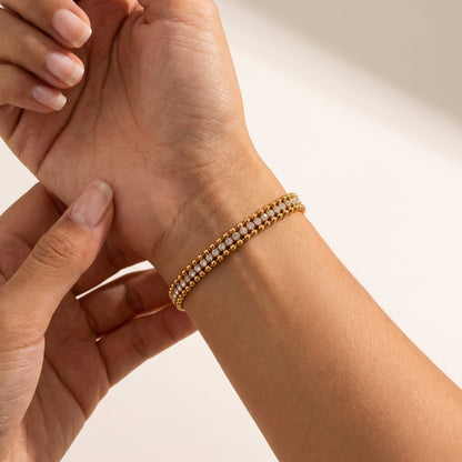 Wider view of a woman wearing the Sofia bead tennis gold bracelet on the wrist