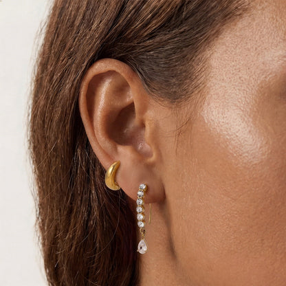 Solène crystal line earring worn in the lobe beside a chunky gold huggie higher on the ear